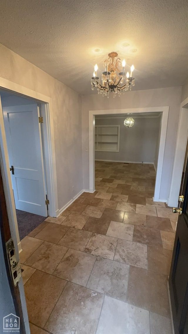 621 W Thomas Ave, Jonesboro, AR 72401 - hallway featuring baseboards, stone finish floor, a textured ceiling, and an inviting chandelier