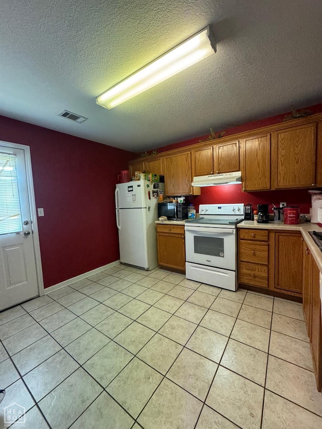 2803 N 4 1/2 St, Paragould, AR 72450 - kitchen with white appliances, under cabinet range hood, brown cabinetry, a textured ceiling, and light countertops