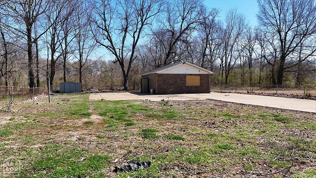 view of yard featuring a patio, concrete driveway, fence, and an outdoor structure