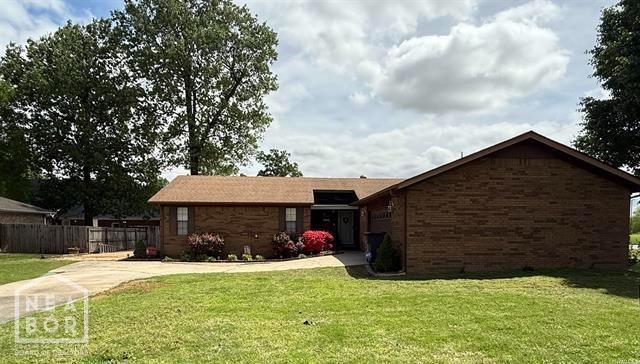 ranch-style home with brick siding, fence, and a front yard