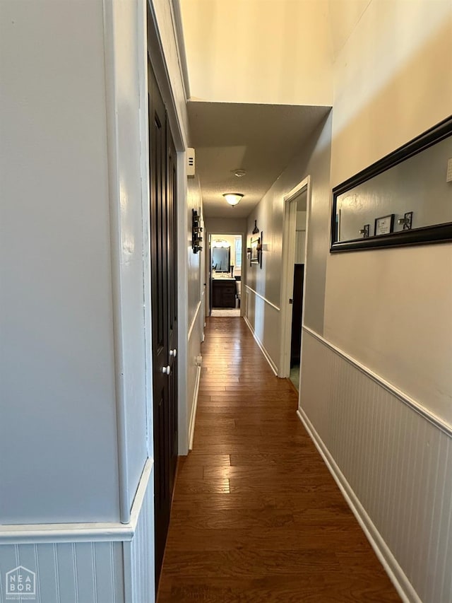 hall with a wainscoted wall and dark wood-type flooring