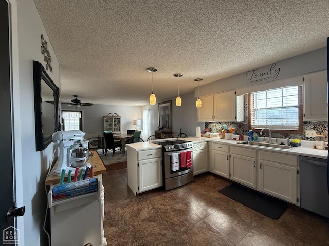 kitchen with a peninsula, a sink, a textured ceiling, a ceiling fan, and appliances with stainless steel finishes