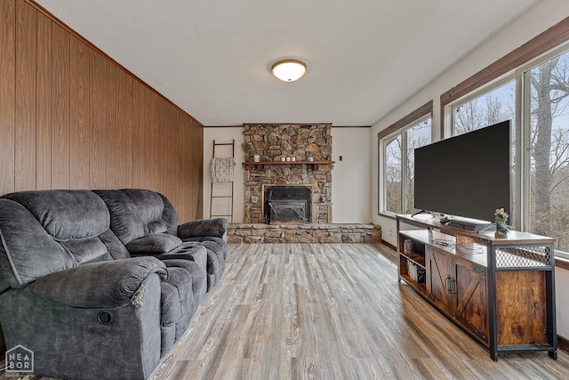 living room featuring wooden walls, baseboards, a fireplace, and wood finished floors