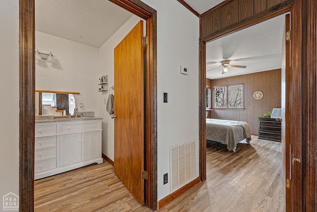 hallway featuring visible vents, baseboards, wooden walls, and light wood-type flooring