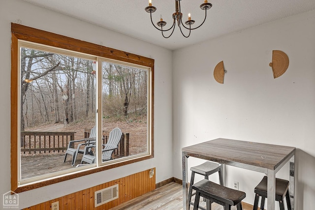 dining space featuring baseboards, a notable chandelier, visible vents, and light wood-style flooring