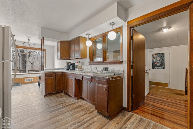 kitchen featuring light wood-style floors, light countertops, a textured ceiling, and visible vents