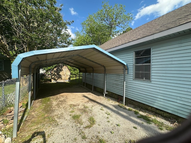 view of parking with fence and a detached carport