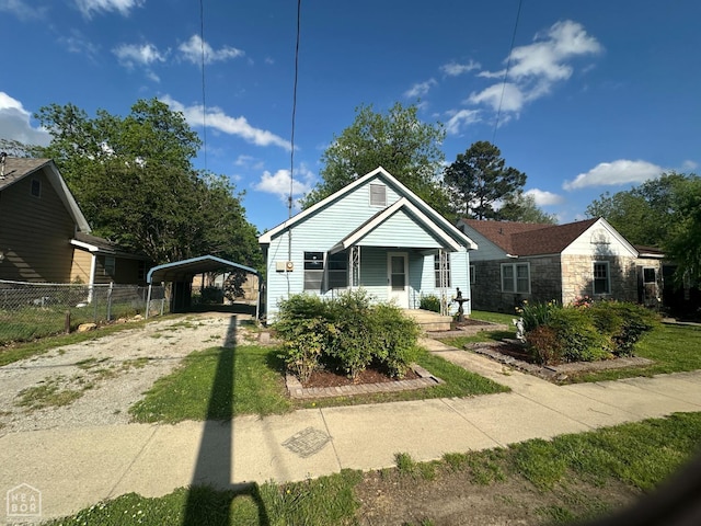 bungalow featuring covered porch, fence, driveway, and a detached carport