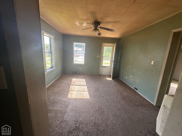 spare room featuring crown molding, carpet, ceiling fan, and baseboards
