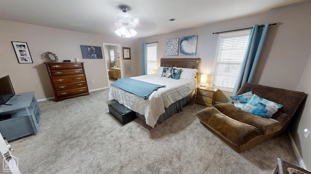 carpeted bedroom with visible vents, baseboards, and connected bathroom