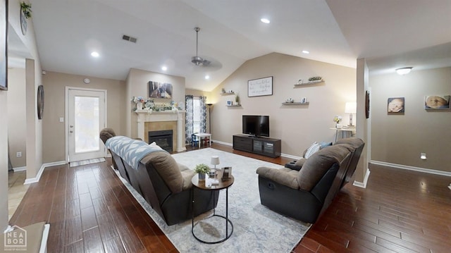 living room featuring baseboards, vaulted ceiling, a tiled fireplace, visible vents, and dark wood finished floors