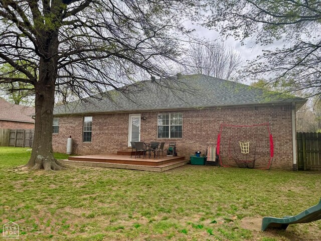 back of house featuring a yard, a wooden deck, fence, and brick siding