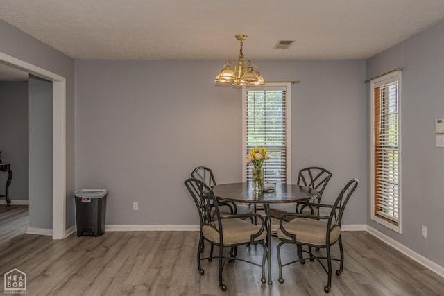 dining space with a notable chandelier, visible vents, plenty of natural light, and wood finished floors