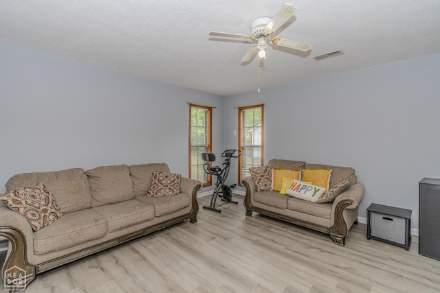 living room featuring baseboards, a ceiling fan, wood finished floors, and visible vents