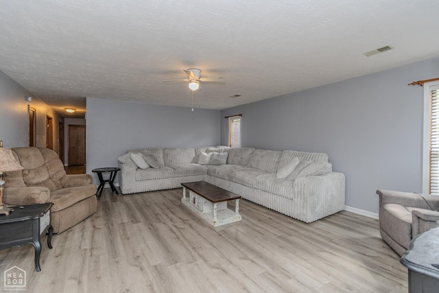 living area featuring a healthy amount of sunlight, a ceiling fan, light wood-type flooring, and visible vents