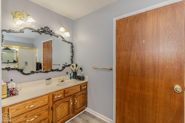 full bathroom with an enclosed shower, baseboards, wood finished floors, and vanity