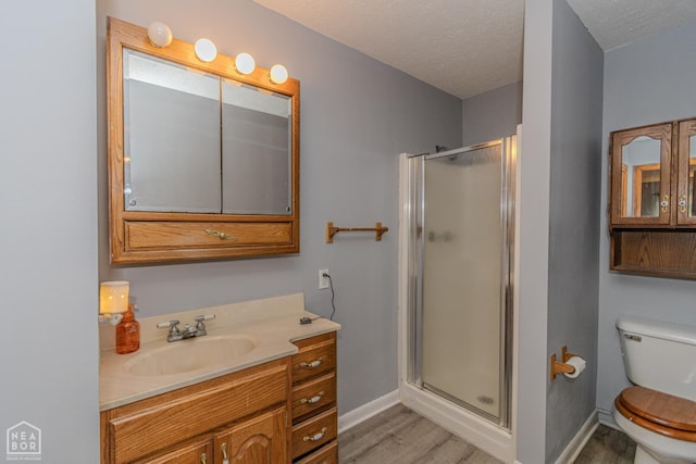 full bath with a textured ceiling, a stall shower, wood finished floors, baseboards, and toilet