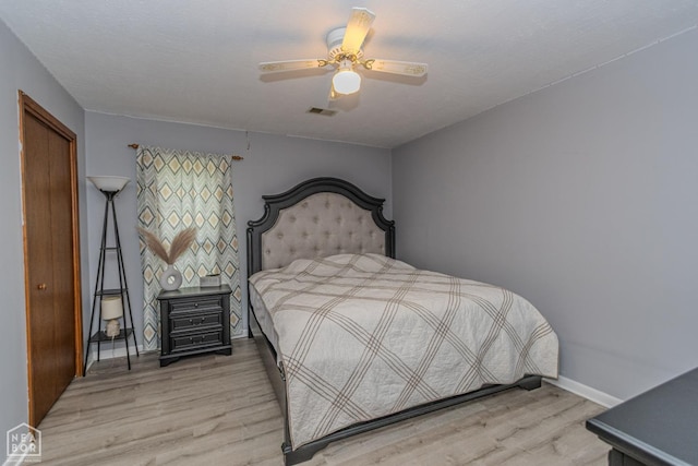 bedroom featuring baseboards, ceiling fan, visible vents, and light wood-style flooring