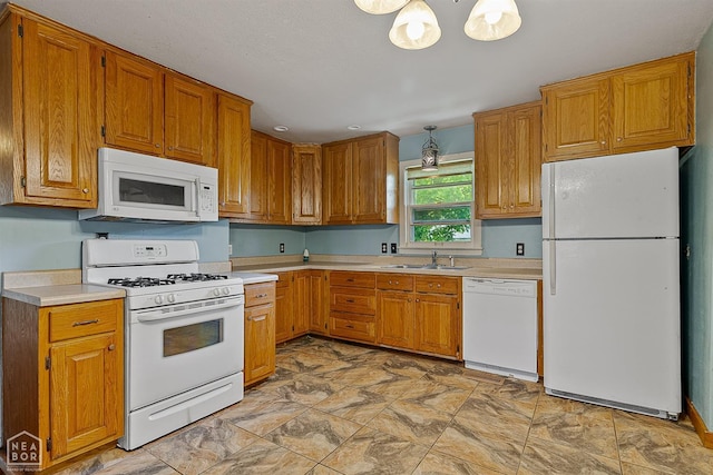kitchen with white appliances, a sink, light countertops, and brown cabinets