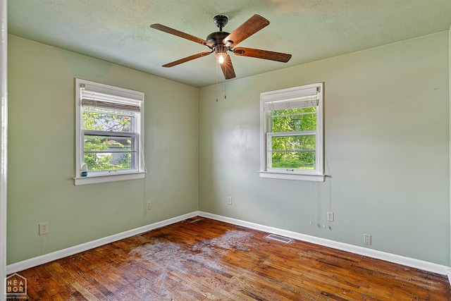 empty room with baseboards, ceiling fan, wood finished floors, and a textured ceiling