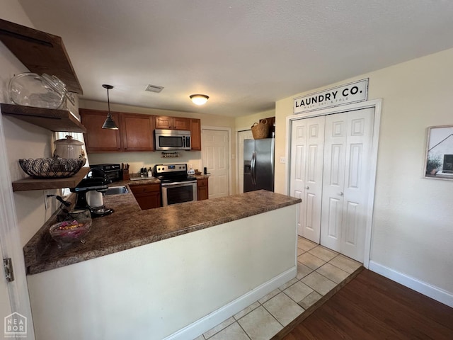 900 Sycamore Cv, Jonesboro, AR 72404 - kitchen with appliances with stainless steel finishes, open shelves, dark countertops, a peninsula, and light tile patterned flooring