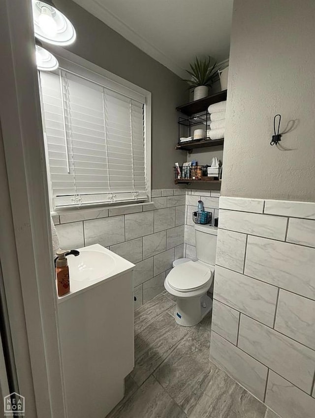 900 Sycamore Cv, Jonesboro, AR 72404 - bathroom featuring tile walls, toilet, marble finish floors, vanity, and a wainscoted wall