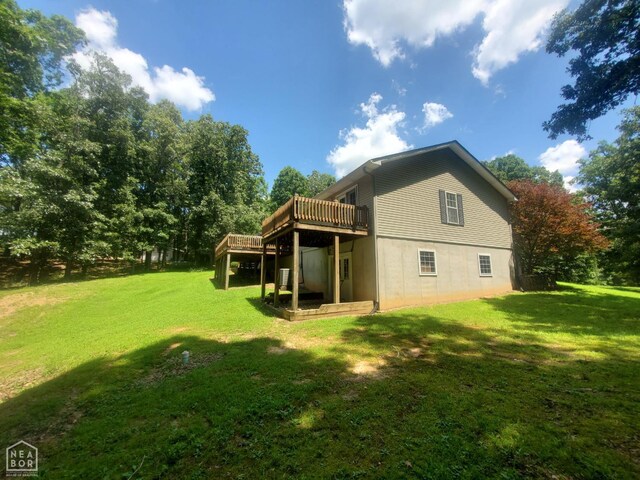 2590 W N St, Piggott, AR 72454 - rear view of house featuring a wooden deck and a lawn