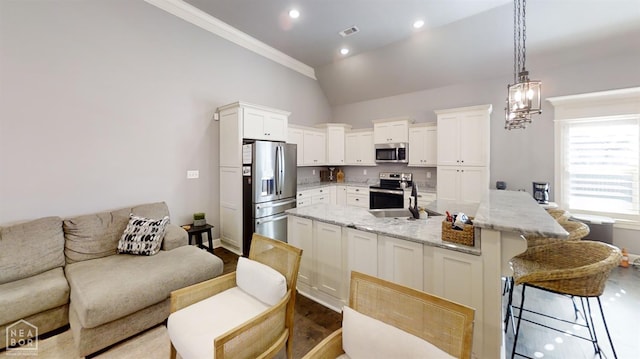 6509 Merrell Dr, Jonesboro, AR 72404 - kitchen with appliances with stainless steel finishes, white cabinets, vaulted ceiling, a kitchen bar, and decorative light fixtures