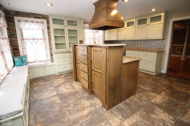 kitchen featuring recessed lighting, island range hood, backsplash, a kitchen island, and light stone counters
