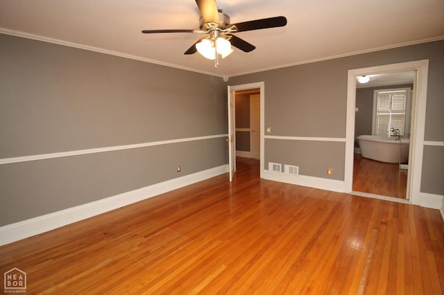unfurnished bedroom featuring baseboards, ornamental molding, a ceiling fan, visible vents, and wood finished floors