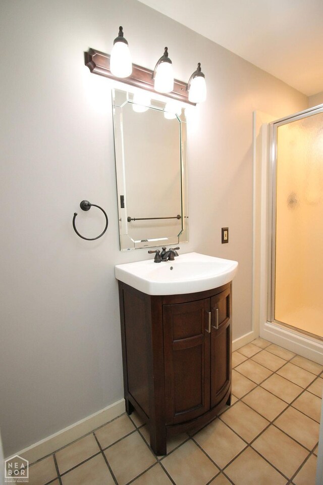 bathroom featuring a stall shower, vanity, baseboards, and tile patterned floors