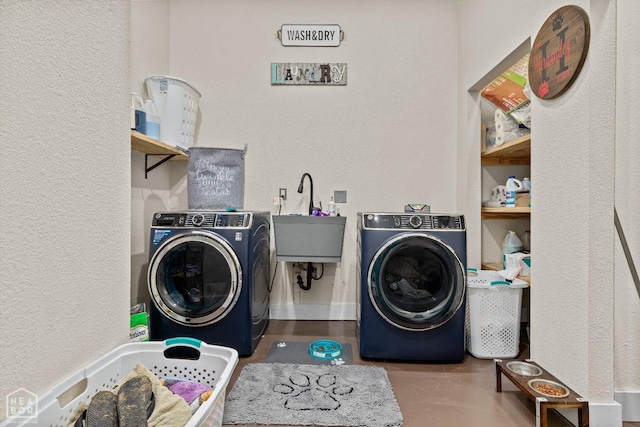 washroom featuring laundry area, separate washer and dryer, a textured wall, and a sink