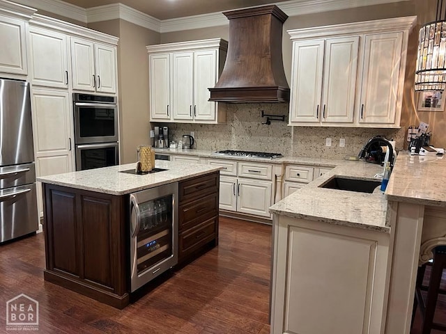 kitchen with appliances with stainless steel finishes, a sink, premium range hood, wine cooler, and decorative backsplash
