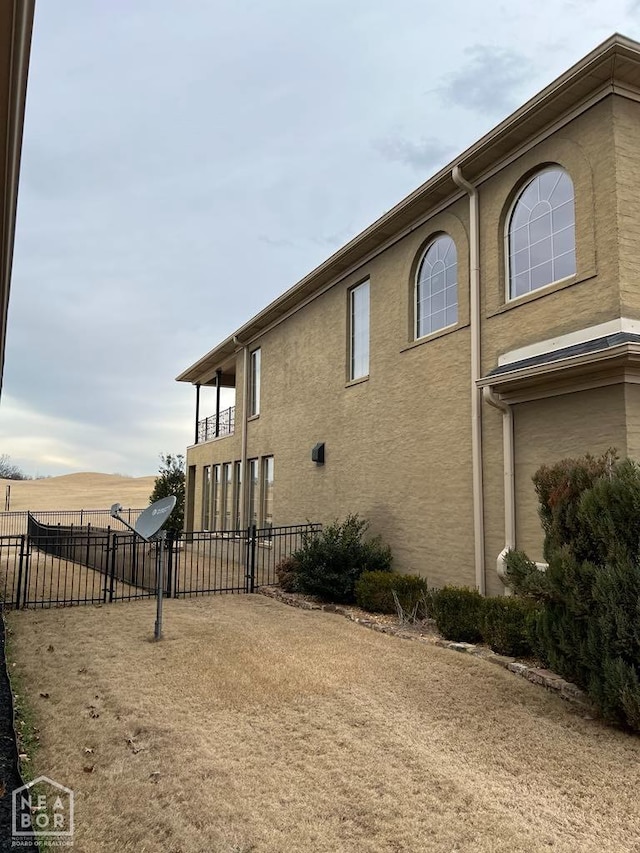 view of side of home featuring stucco siding and fence