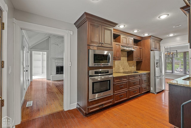 2203 Rankin Cir, Jonesboro, AR 72404 - kitchen featuring stainless steel appliances, light wood-style floors, under cabinet range hood, light stone countertops, and tasteful backsplash