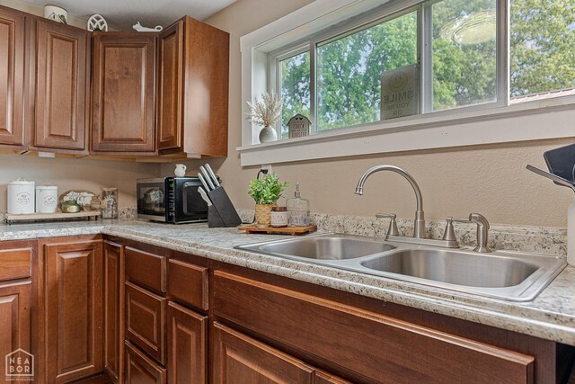 215 N Nance St, Monette, AR 72447 - kitchen with black microwave, a sink, light countertops, and brown cabinets