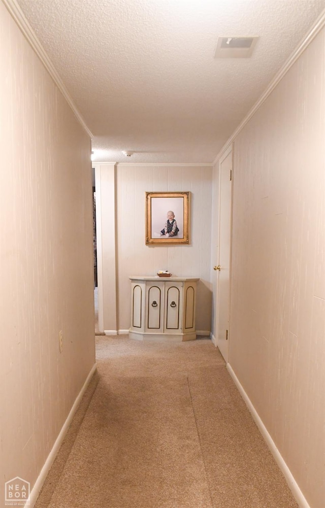 hallway featuring baseboards, carpet flooring, a textured ceiling, and crown molding