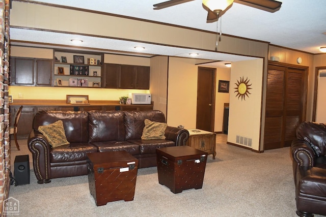 living area with a ceiling fan, carpet, ornamental molding, and visible vents