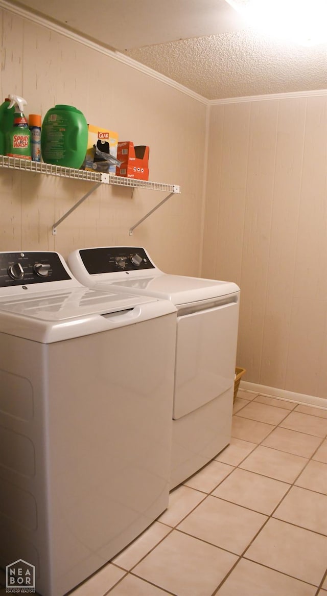 laundry area with light tile patterned floors, separate washer and dryer, laundry area, and crown molding
