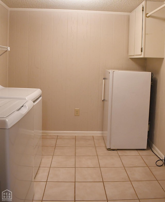 clothes washing area featuring a textured ceiling, light tile patterned flooring, cabinet space, and washer and clothes dryer
