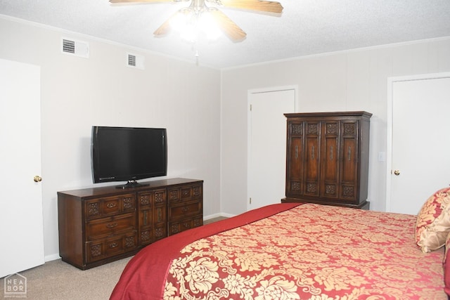 carpeted bedroom with ornamental molding, visible vents, a ceiling fan, and a textured ceiling