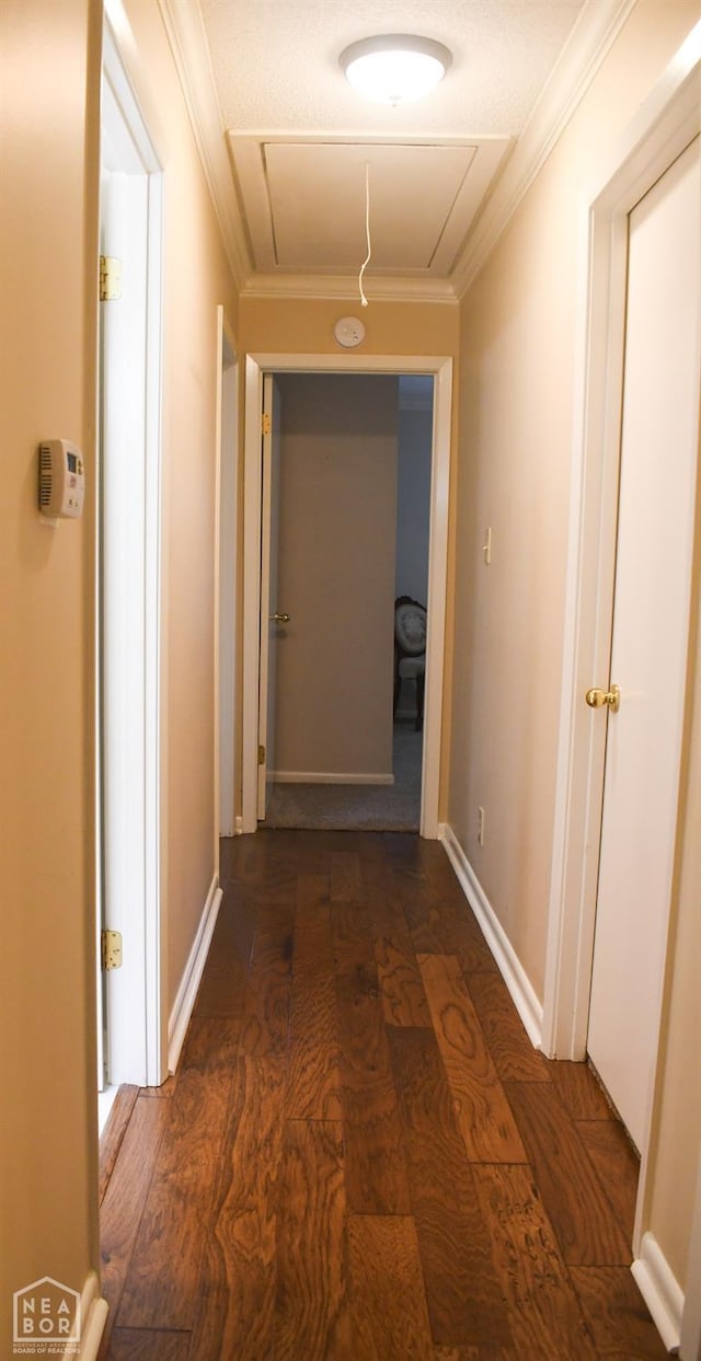 hallway featuring ornamental molding, attic access, and dark wood finished floors