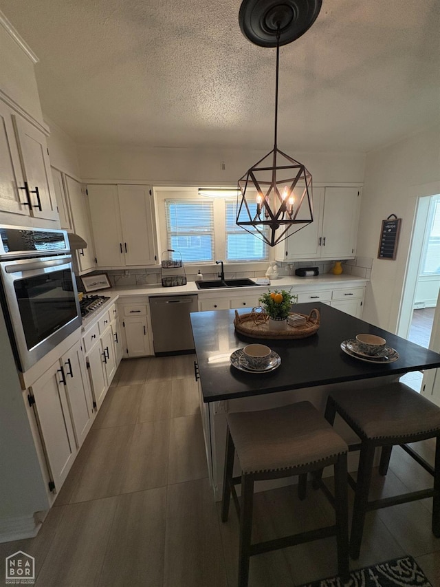 608 W Poplar St W, Paragould, AR 72450 - kitchen featuring a textured ceiling, a sink, white cabinets, a notable chandelier, and stainless steel appliances