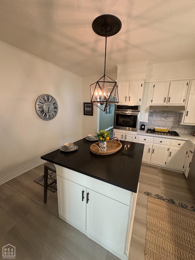 608 W Poplar St W, Paragould, AR 72450 - kitchen with a center island, a textured ceiling, white cabinets, backsplash, and stainless steel appliances