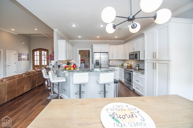 kitchen with a notable chandelier, crown molding, white cabinets, dark wood-type flooring, and appliances with stainless steel finishes