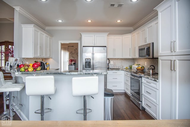 kitchen featuring a peninsula, visible vents, white cabinetry, and appliances with stainless steel finishes