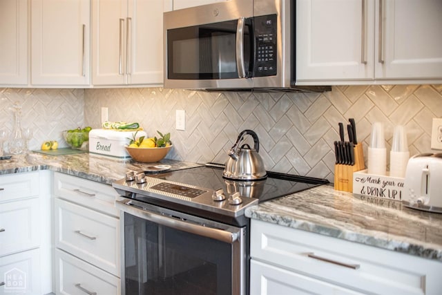 kitchen with tasteful backsplash, light stone countertops, white cabinetry, and stainless steel appliances