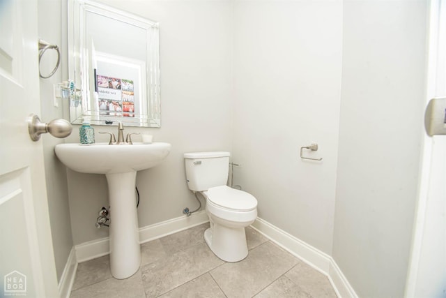 bathroom with tile patterned flooring, baseboards, and toilet