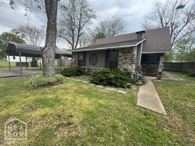 view of front of house featuring stone siding, fence, and a front yard