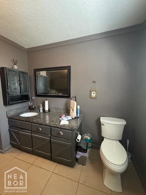 half bath featuring tile patterned floors, vanity, a textured ceiling, and toilet